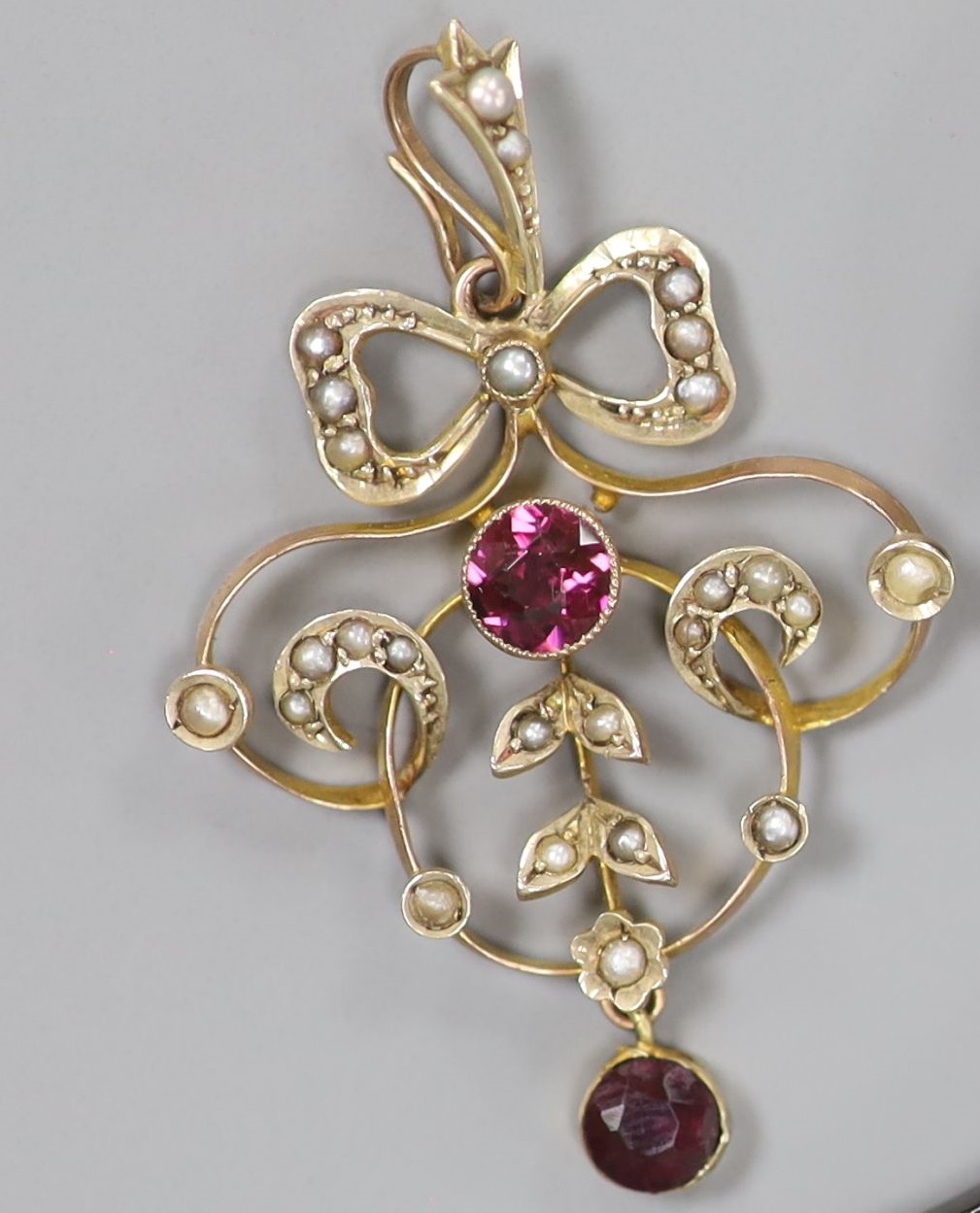 An early 20th century 9ct, garnet and seed pearl set openwork pendant